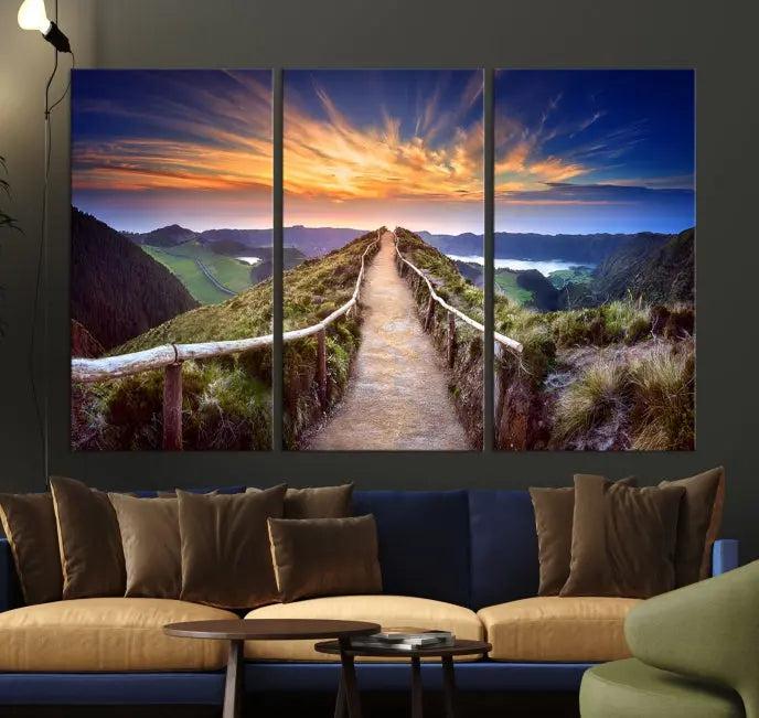 The Mountain and Sunset Wall Art Canvas Print, featuring a three-panel design on museum-quality canvas, captures a stunning sunset over a mountain path with a wooden railing. The hand-assembled frame ensures an exquisite finish and arrives ready to hang, adding natural beauty to any environment.