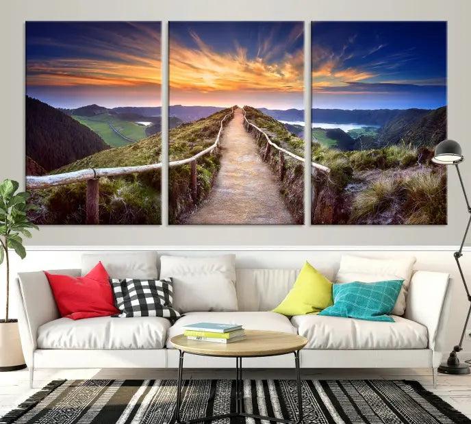 The Mountain and Sunset Wall Art Canvas Print, featuring a three-panel design on museum-quality canvas, captures a stunning sunset over a mountain path with a wooden railing. The hand-assembled frame ensures an exquisite finish and arrives ready to hang, adding natural beauty to any environment.