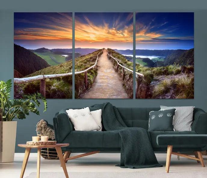 The Mountain and Sunset Wall Art Canvas Print, featuring a three-panel design on museum-quality canvas, captures a stunning sunset over a mountain path with a wooden railing. The hand-assembled frame ensures an exquisite finish and arrives ready to hang, adding natural beauty to any environment.