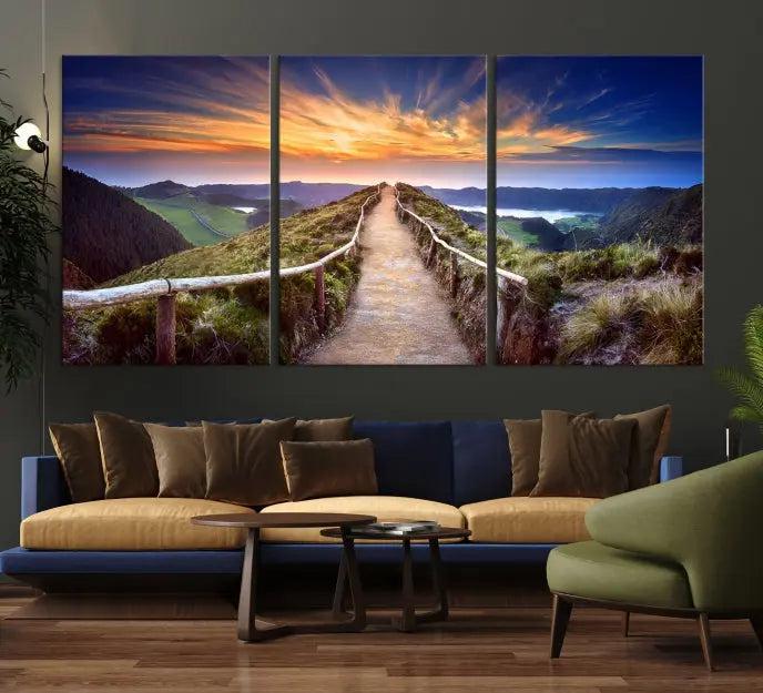 The Mountain and Sunset Wall Art Canvas Print, featuring a three-panel design on museum-quality canvas, captures a stunning sunset over a mountain path with a wooden railing. The hand-assembled frame ensures an exquisite finish and arrives ready to hang, adding natural beauty to any environment.