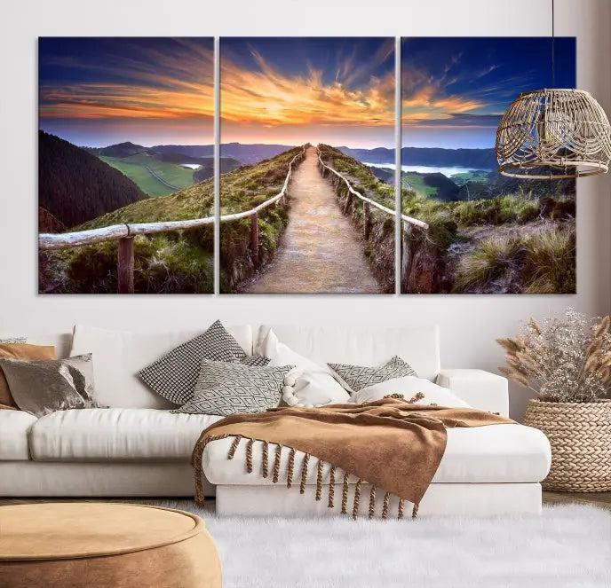 The Mountain and Sunset Wall Art Canvas Print, featuring a three-panel design on museum-quality canvas, captures a stunning sunset over a mountain path with a wooden railing. The hand-assembled frame ensures an exquisite finish and arrives ready to hang, adding natural beauty to any environment.