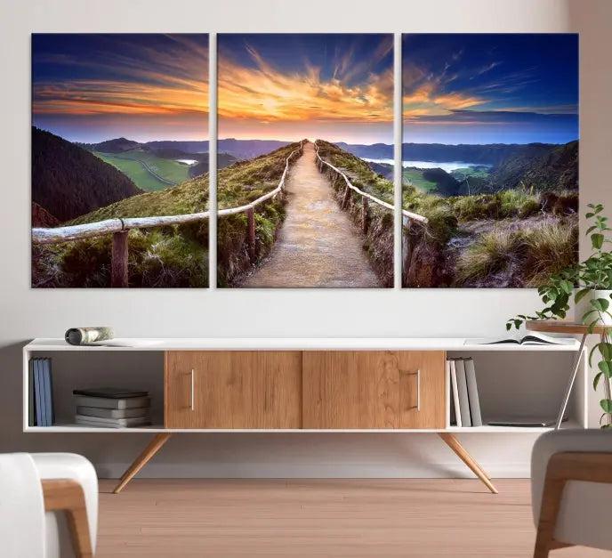 The Mountain and Sunset Wall Art Canvas Print, featuring a three-panel design on museum-quality canvas, captures a stunning sunset over a mountain path with a wooden railing. The hand-assembled frame ensures an exquisite finish and arrives ready to hang, adding natural beauty to any environment.