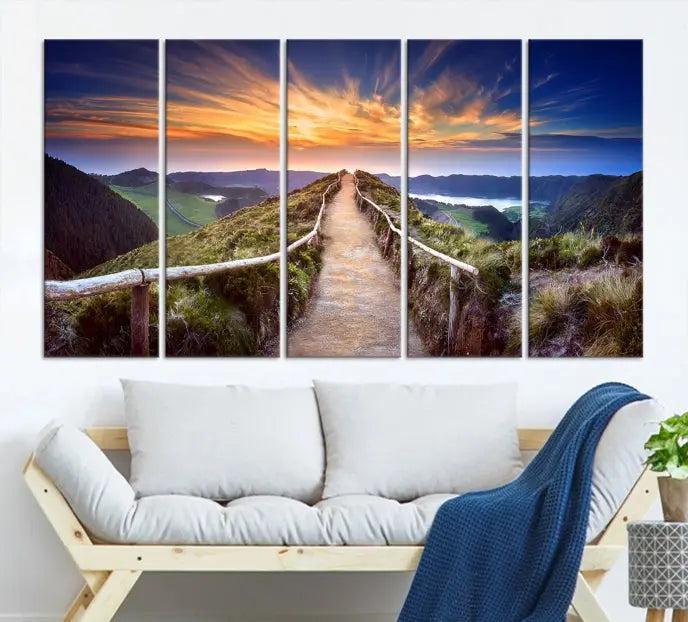 The Mountain and Sunset Wall Art Canvas Print, featuring a three-panel design on museum-quality canvas, captures a stunning sunset over a mountain path with a wooden railing. The hand-assembled frame ensures an exquisite finish and arrives ready to hang, adding natural beauty to any environment.