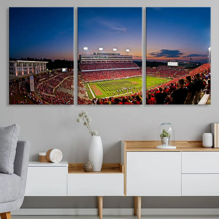 A thrilling college football game is captured in the NC State Wolfpack Football Team Print, featuring a triptych wall art of the packed Carter-Finley Stadium at sunset, showcasing NC State Wolfpack fans and players on the field.