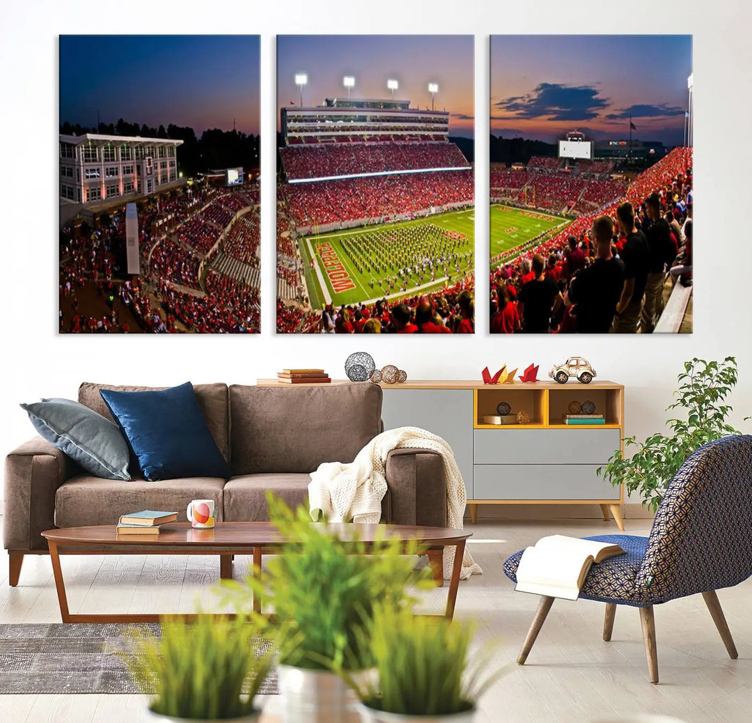 The living room features a three-panel NC State Wolfpack Football Team Print of Raleigh Carter-Finley Stadium, capturing the stadium at sunset. Each piece offers a gallery-quality finish that beautifully unifies the space.