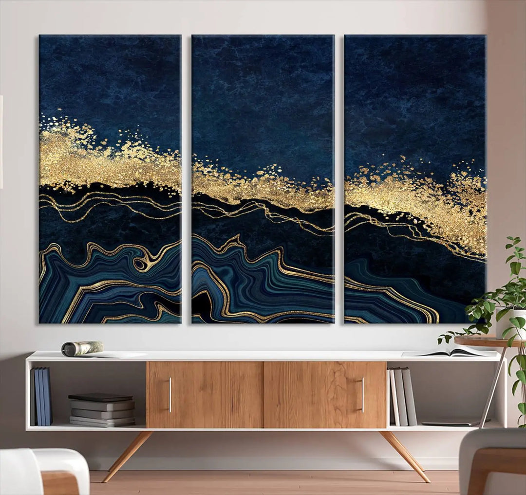 A modern living room featuring a ready-to-hang Navy Blue Marble Fluid Effect Large Wall Art, a stunning abstract triptych on museum-quality canvas in blue and gold. The artwork's vibrant colors are preserved with an enhanced UV-protective coating.