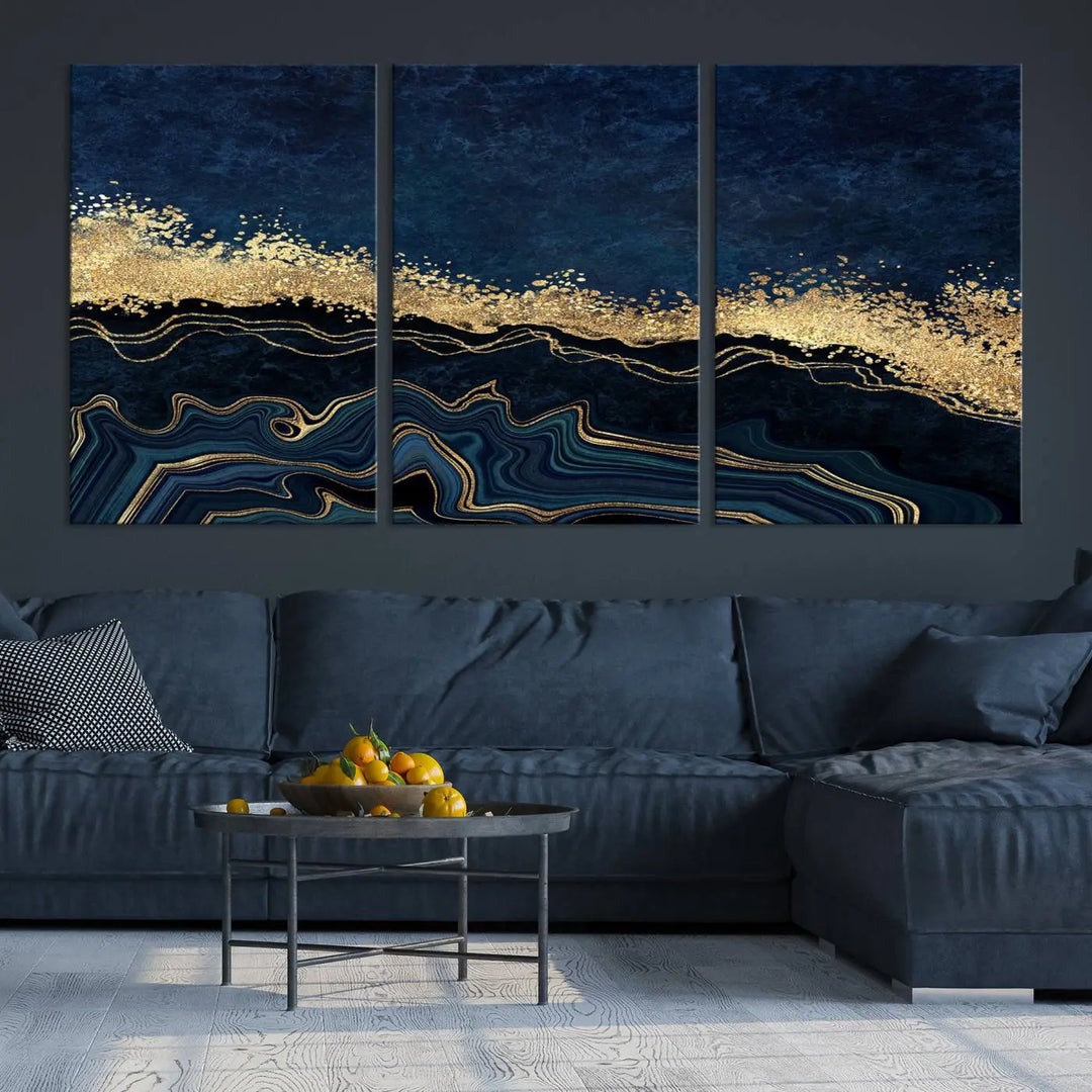 A modern living room featuring a ready-to-hang Navy Blue Marble Fluid Effect Large Wall Art, a stunning abstract triptych on museum-quality canvas in blue and gold. The artwork's vibrant colors are preserved with an enhanced UV-protective coating.