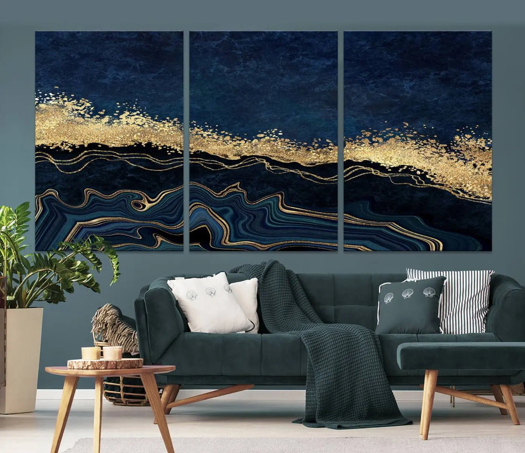 A modern living room featuring a ready-to-hang Navy Blue Marble Fluid Effect Large Wall Art, a stunning abstract triptych on museum-quality canvas in blue and gold. The artwork's vibrant colors are preserved with an enhanced UV-protective coating.