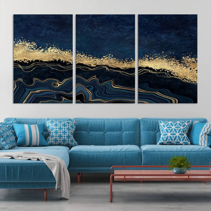 A modern living room featuring a ready-to-hang Navy Blue Marble Fluid Effect Large Wall Art, a stunning abstract triptych on museum-quality canvas in blue and gold. The artwork's vibrant colors are preserved with an enhanced UV-protective coating.