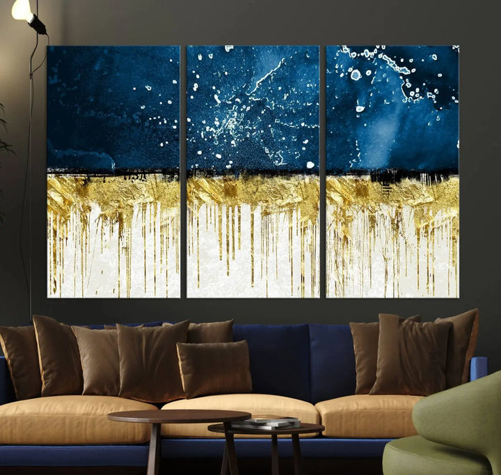 The Navy Blue Marble Fluid Effect Wall Art Abstract Canvas Print, a three-panel piece featuring blue, gold, and white colors on gallery-wrapped canvas, adorns the wall in a modern room. The museum-quality canvas ensures an elegant touch.