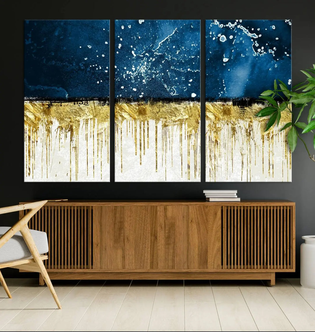 The Navy Blue Marble Fluid Effect Wall Art Abstract Canvas Print, a three-panel piece featuring blue, gold, and white colors on gallery-wrapped canvas, adorns the wall in a modern room. The museum-quality canvas ensures an elegant touch.