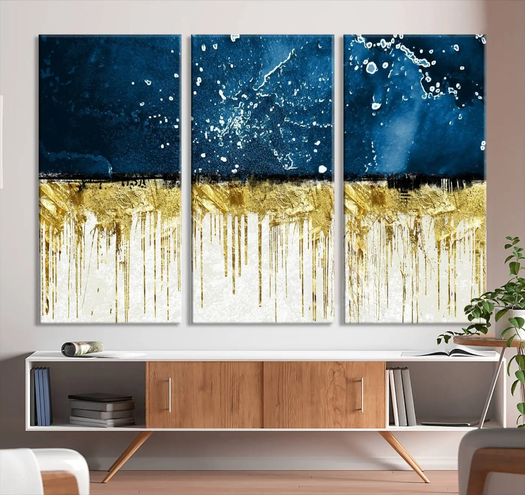 The Navy Blue Marble Fluid Effect Wall Art Abstract Canvas Print, a three-panel piece featuring blue, gold, and white colors on gallery-wrapped canvas, adorns the wall in a modern room. The museum-quality canvas ensures an elegant touch.