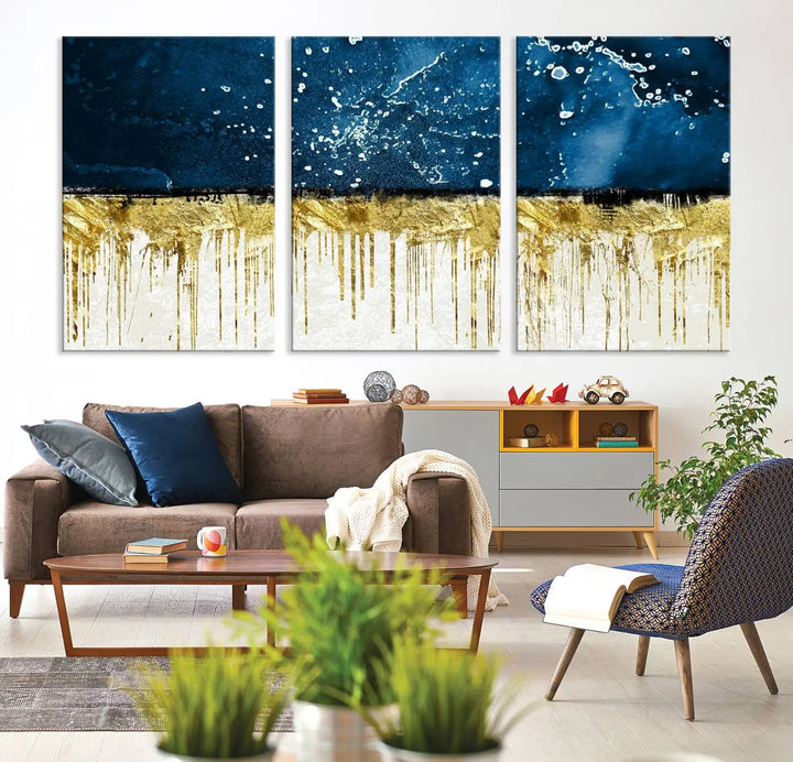 The Navy Blue Marble Fluid Effect Wall Art Abstract Canvas Print, a three-panel piece featuring blue, gold, and white colors on gallery-wrapped canvas, adorns the wall in a modern room. The museum-quality canvas ensures an elegant touch.