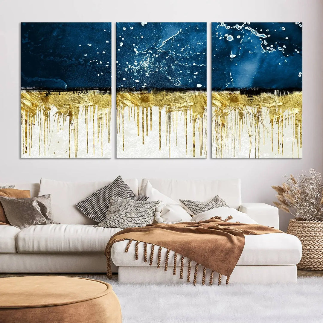 The Navy Blue Marble Fluid Effect Wall Art Abstract Canvas Print, a three-panel piece featuring blue, gold, and white colors on gallery-wrapped canvas, adorns the wall in a modern room. The museum-quality canvas ensures an elegant touch.