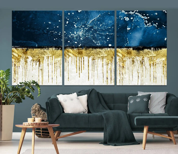 The Navy Blue Marble Fluid Effect Wall Art Abstract Canvas Print, a three-panel piece featuring blue, gold, and white colors on gallery-wrapped canvas, adorns the wall in a modern room. The museum-quality canvas ensures an elegant touch.