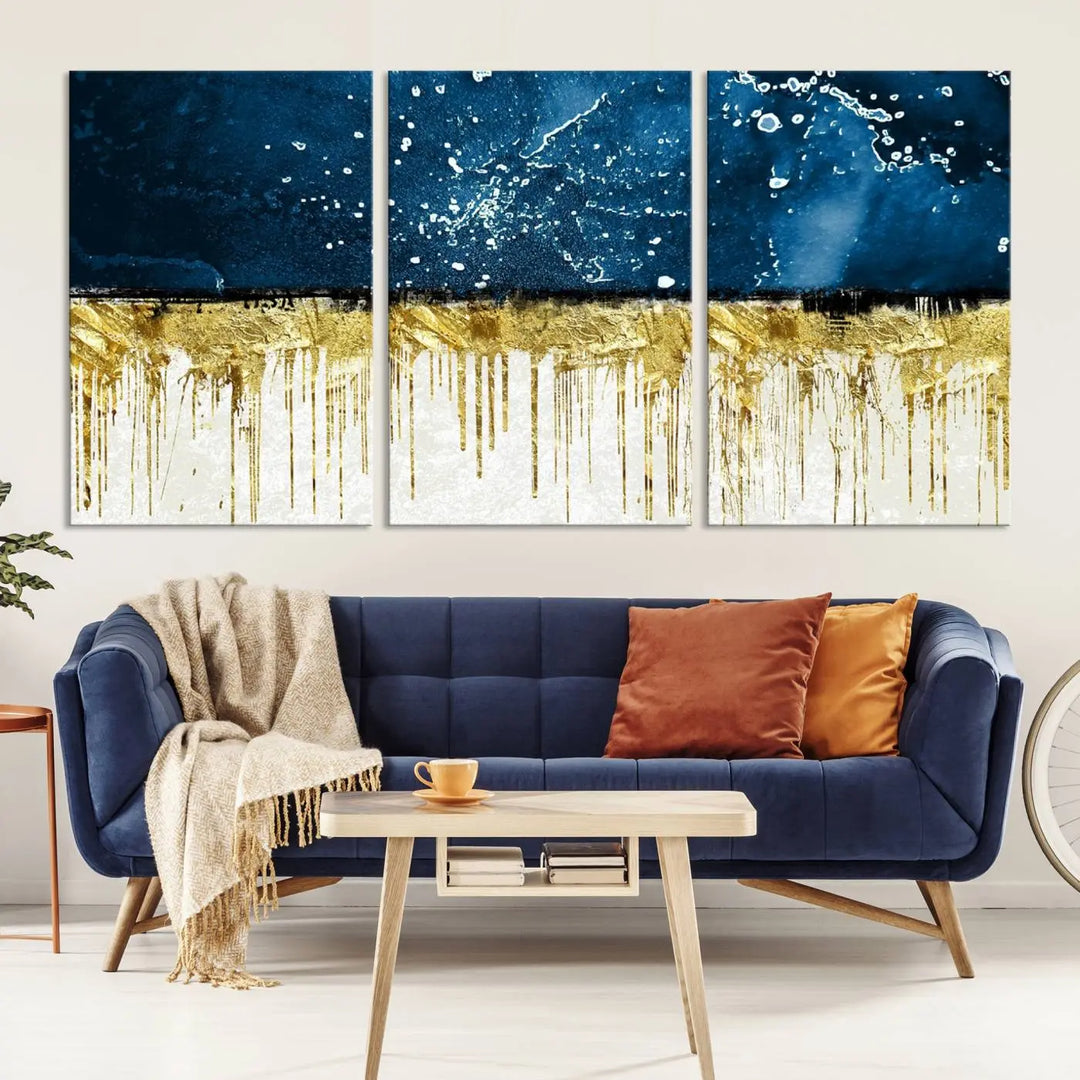 The Navy Blue Marble Fluid Effect Wall Art Abstract Canvas Print, a three-panel piece featuring blue, gold, and white colors on gallery-wrapped canvas, adorns the wall in a modern room. The museum-quality canvas ensures an elegant touch.