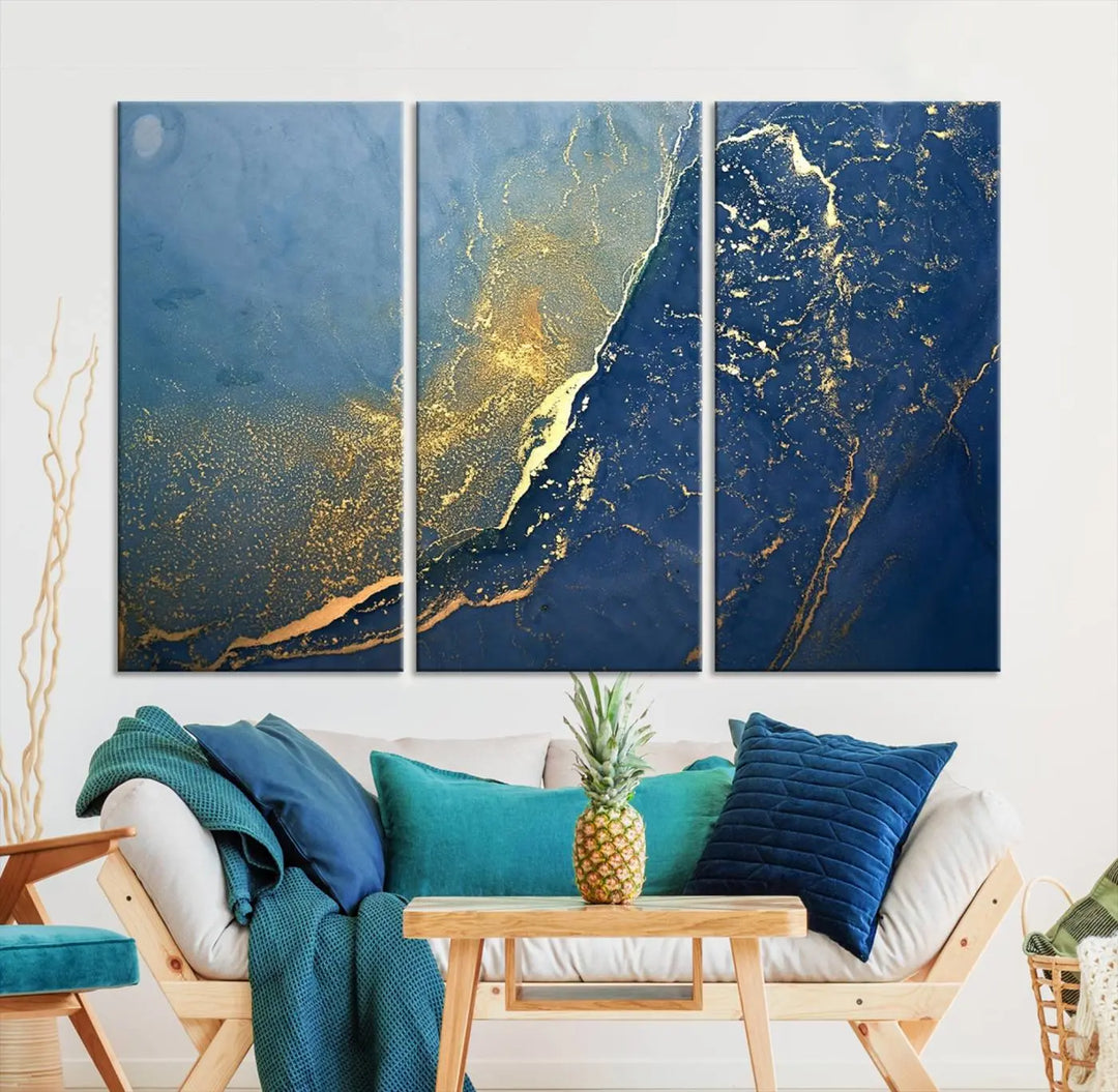 The Navy Blue Yellow Twinkle Wall Art Canvas Print, featuring an abstract design in gold and blue, enhances a modern living room as it adorns a white wall with its gallery-wrapped, museum-quality canvases for an exquisite touch.