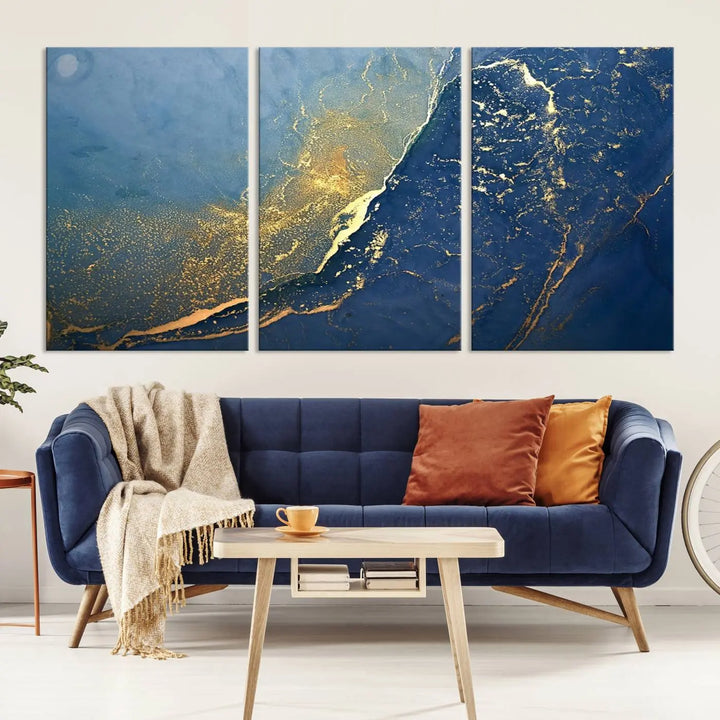 The Navy Blue Yellow Twinkle Wall Art Canvas Print, featuring an abstract design in gold and blue, enhances a modern living room as it adorns a white wall with its gallery-wrapped, museum-quality canvases for an exquisite touch.