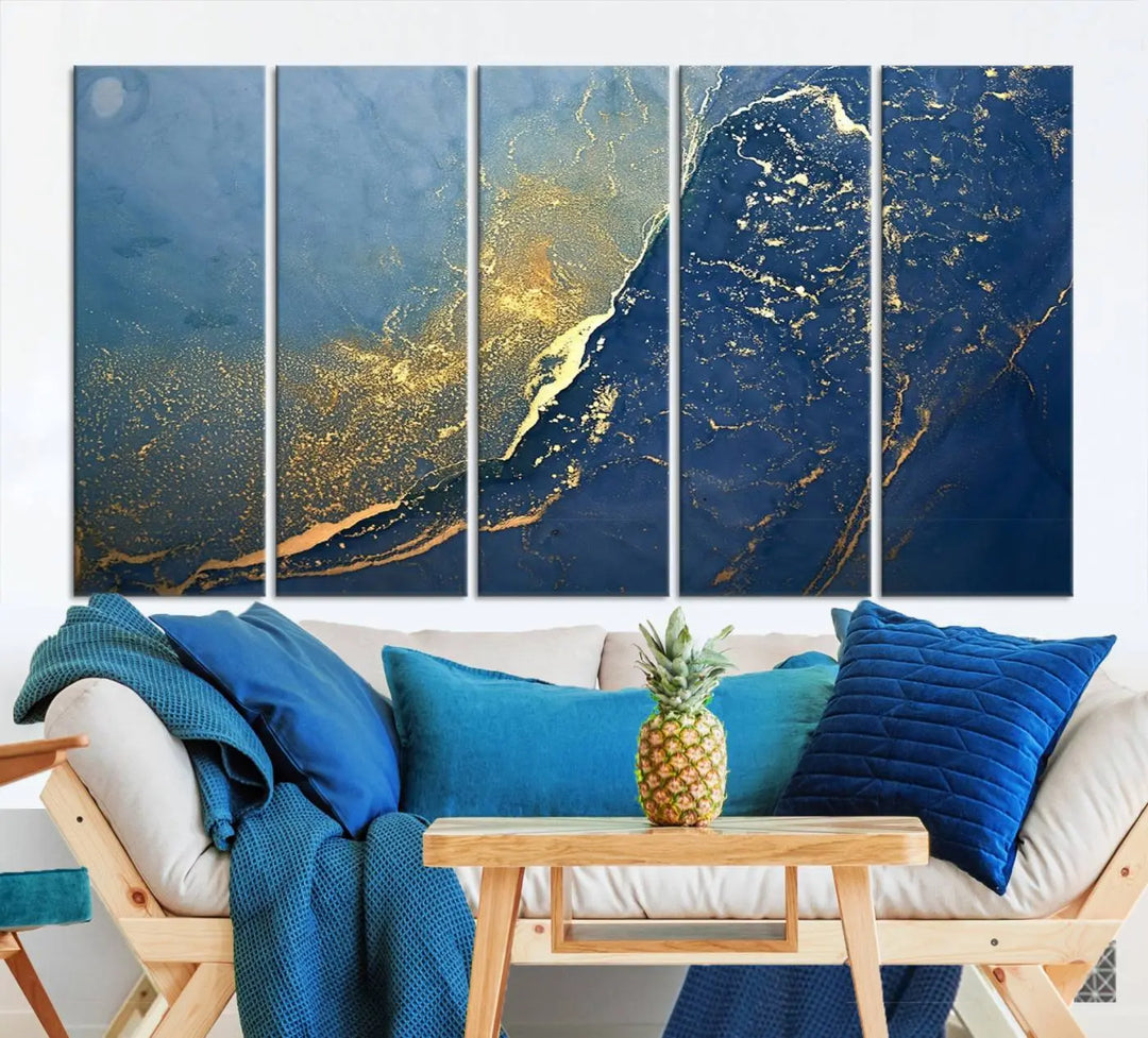 The Navy Blue Yellow Twinkle Wall Art Canvas Print, featuring an abstract design in gold and blue, enhances a modern living room as it adorns a white wall with its gallery-wrapped, museum-quality canvases for an exquisite touch.