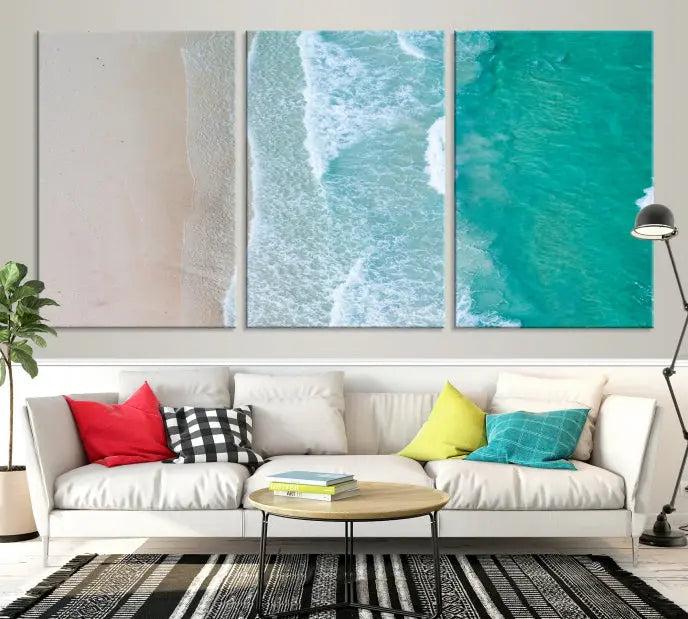 The space above the dark blue sofa is beautifully adorned with the Ocean Aerial Wall Art Canvas Print, featuring a breathtaking aerial beach view spread across five panels. Crafted on gallery-wrapped, museum-quality canvas with a UV-protective coating, it creates an impressive visual display.