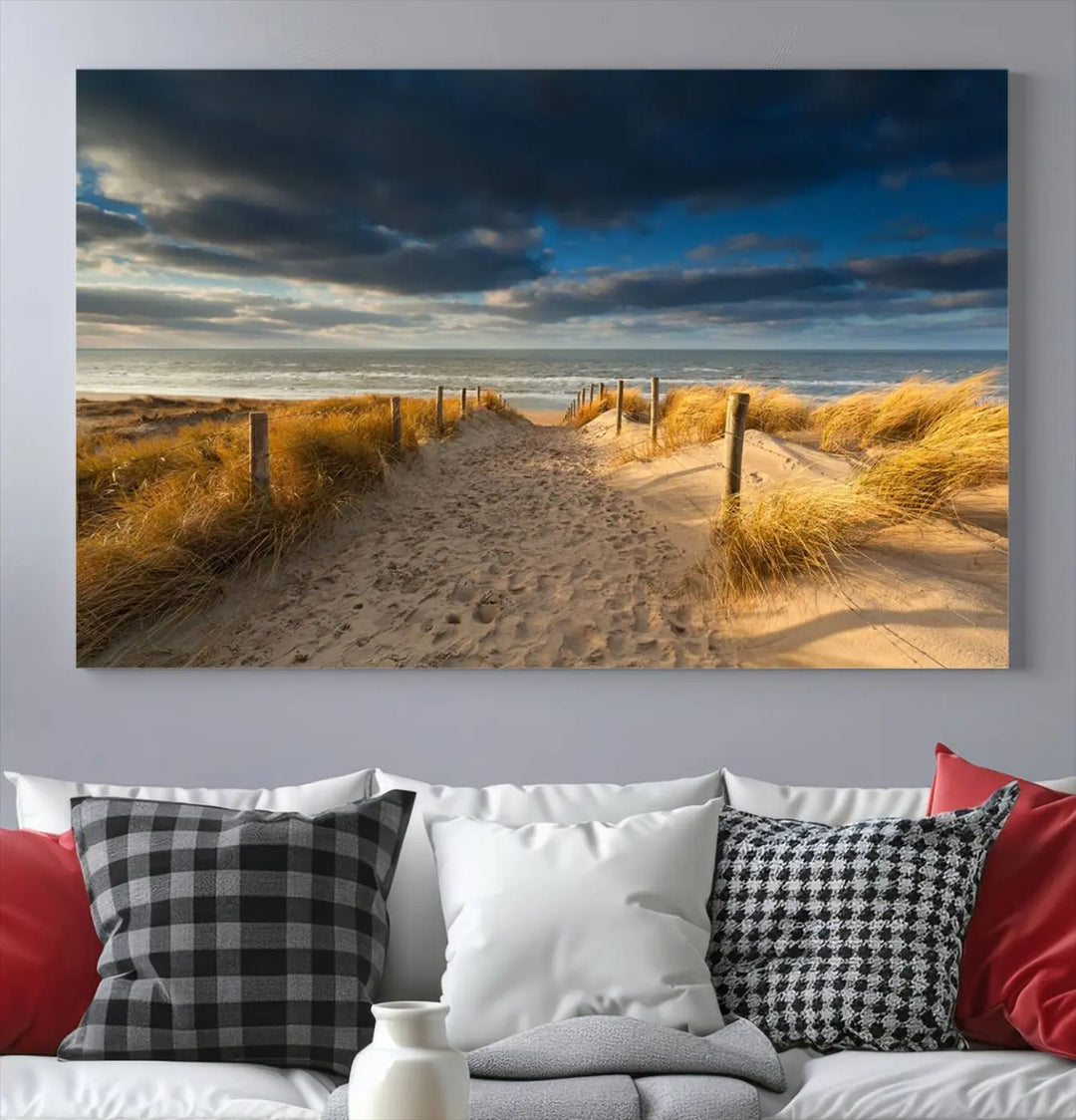 The Ocean Beach Dark Clouds Wall Art Canvas Print is a breathtaking triptych depicting a sandy beach path with tall grasses under an intense cloudy sky. It is crafted on museum-quality canvas with UV protection.