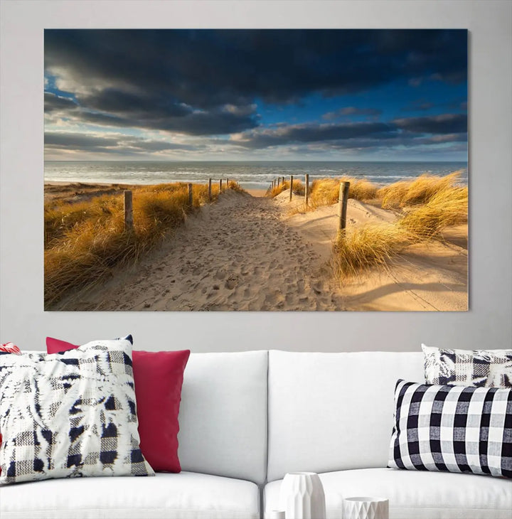 The Ocean Beach Dark Clouds Wall Art Canvas Print is a breathtaking triptych depicting a sandy beach path with tall grasses under an intense cloudy sky. It is crafted on museum-quality canvas with UV protection.