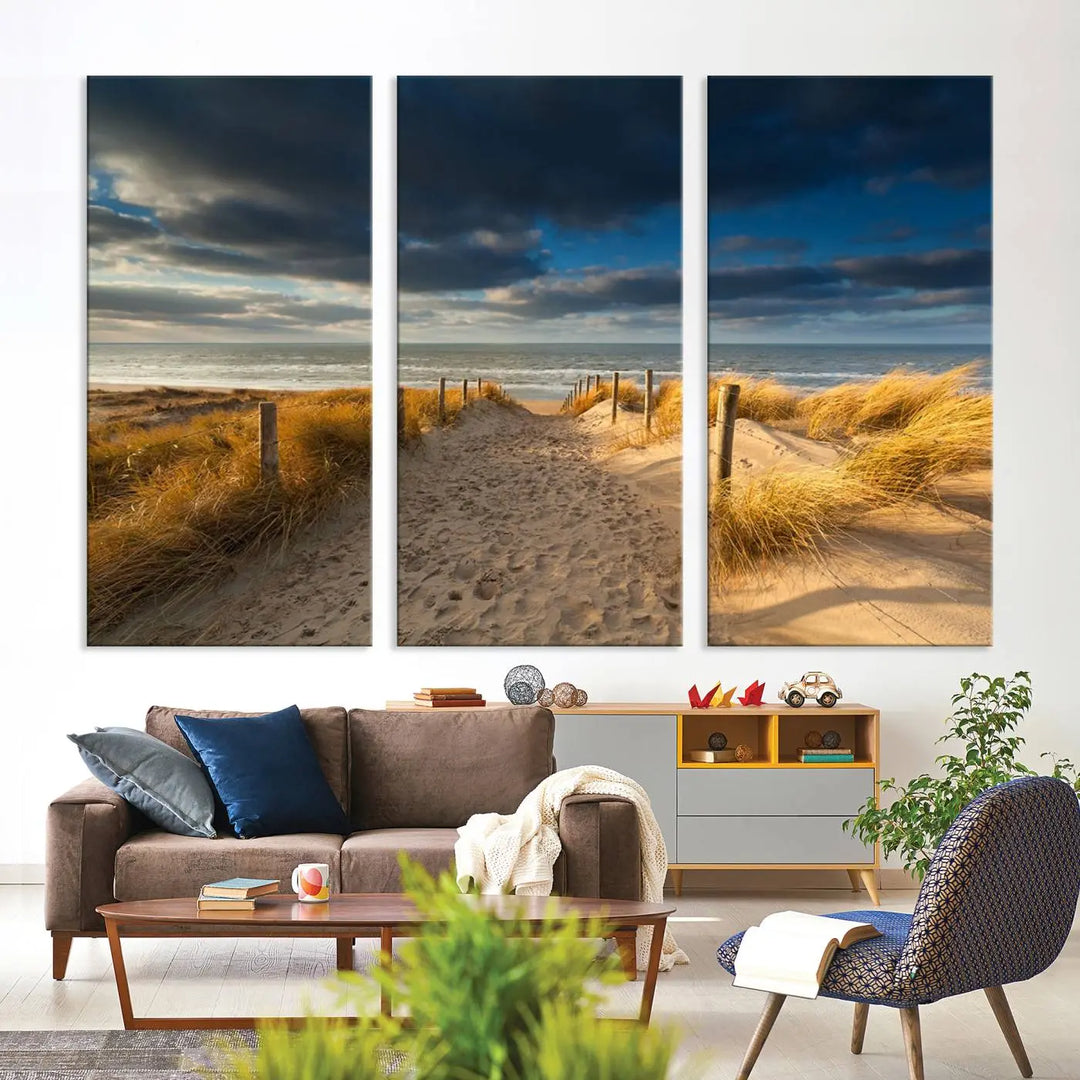 The Ocean Beach Dark Clouds Wall Art Canvas Print is a breathtaking triptych depicting a sandy beach path with tall grasses under an intense cloudy sky. It is crafted on museum-quality canvas with UV protection.