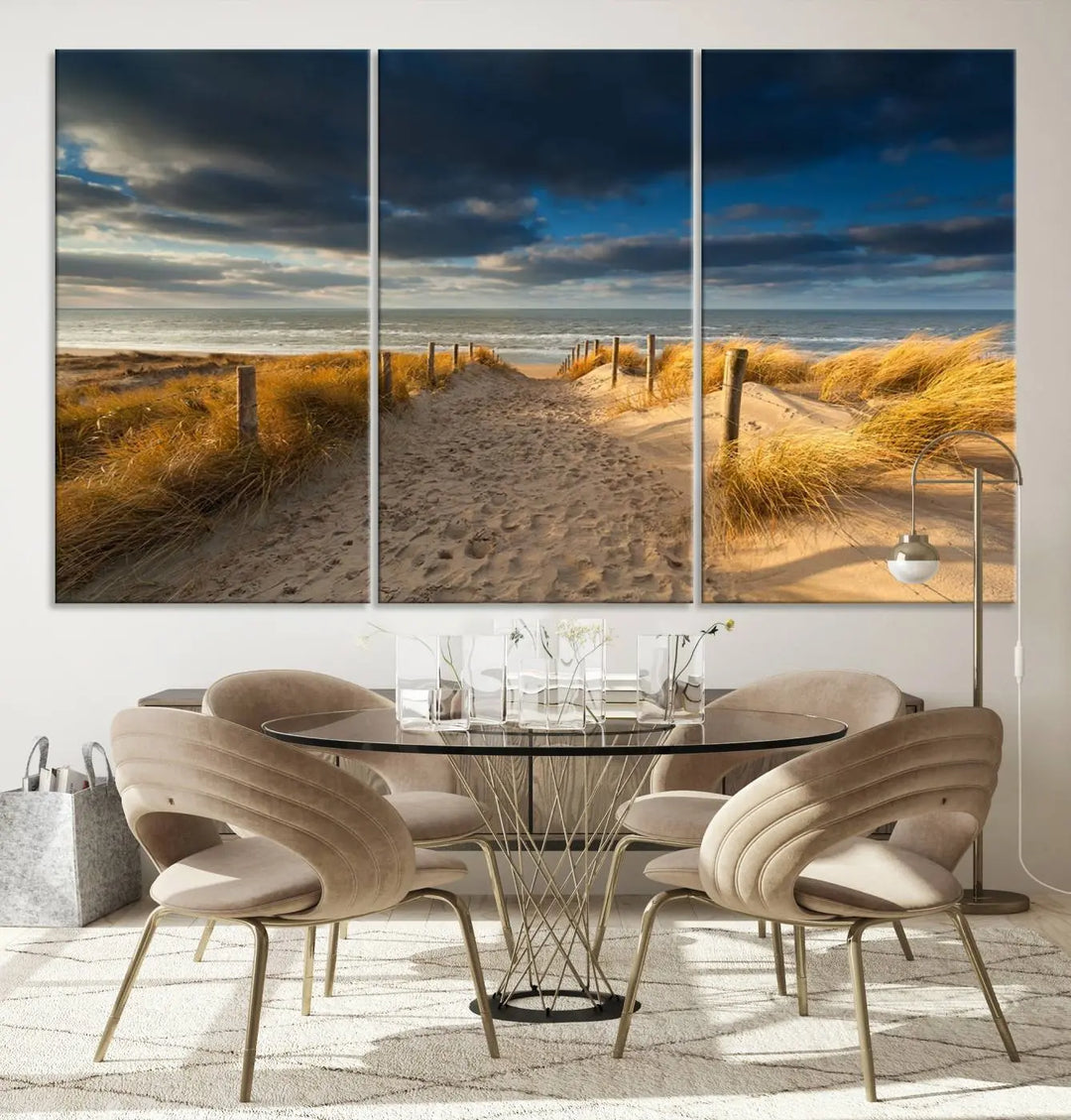 The Ocean Beach Dark Clouds Wall Art Canvas Print is a breathtaking triptych depicting a sandy beach path with tall grasses under an intense cloudy sky. It is crafted on museum-quality canvas with UV protection.