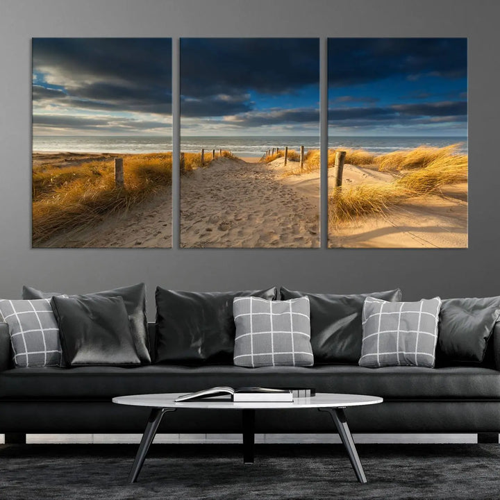 The Ocean Beach Dark Clouds Wall Art Canvas Print is a breathtaking triptych depicting a sandy beach path with tall grasses under an intense cloudy sky. It is crafted on museum-quality canvas with UV protection.