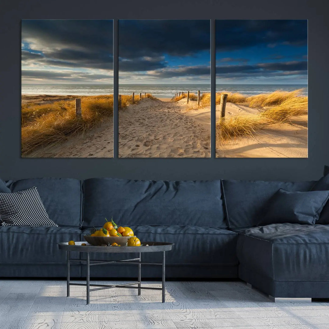 The Ocean Beach Dark Clouds Wall Art Canvas Print is a breathtaking triptych depicting a sandy beach path with tall grasses under an intense cloudy sky. It is crafted on museum-quality canvas with UV protection.