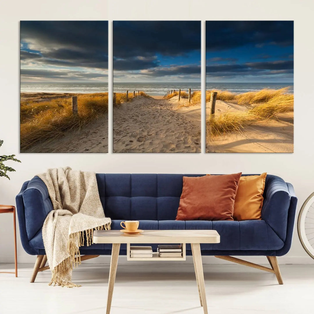 The Ocean Beach Dark Clouds Wall Art Canvas Print is a breathtaking triptych depicting a sandy beach path with tall grasses under an intense cloudy sky. It is crafted on museum-quality canvas with UV protection.