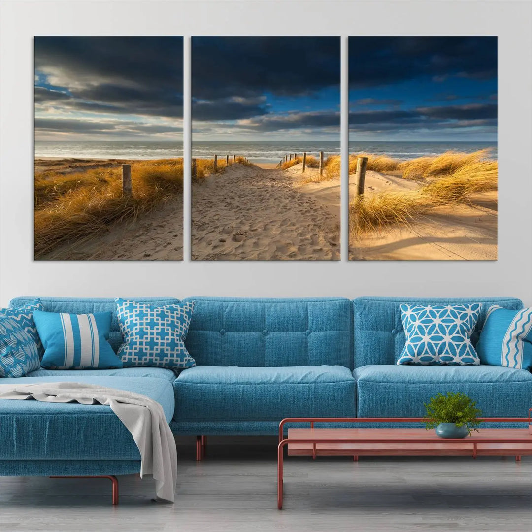 The Ocean Beach Dark Clouds Wall Art Canvas Print is a breathtaking triptych depicting a sandy beach path with tall grasses under an intense cloudy sky. It is crafted on museum-quality canvas with UV protection.