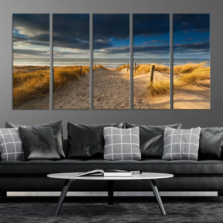 The Ocean Beach Dark Clouds Wall Art Canvas Print is a breathtaking triptych depicting a sandy beach path with tall grasses under an intense cloudy sky. It is crafted on museum-quality canvas with UV protection.