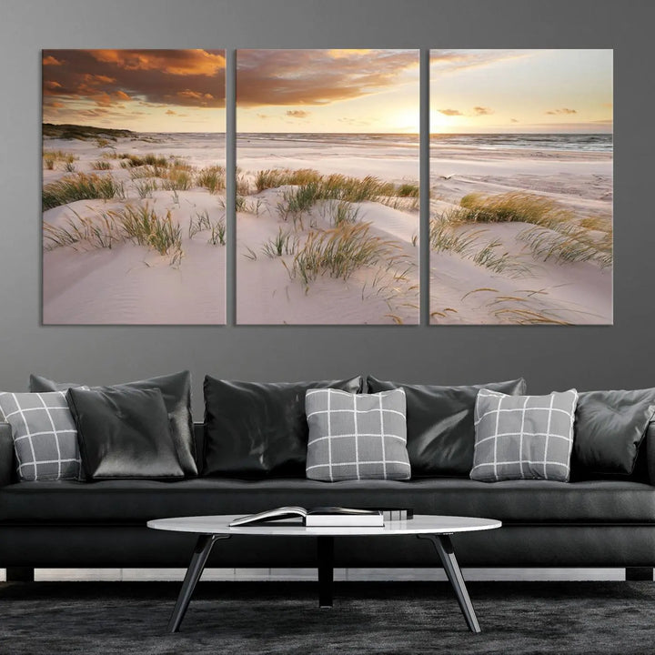 A triptych of the Ocean Beach Wall Art Canvas Print Sunset Artwork Print Coastal Wall Art showcases a serene beach landscape with sand dunes and grasses, gallery wrapped on museum-quality canvas.