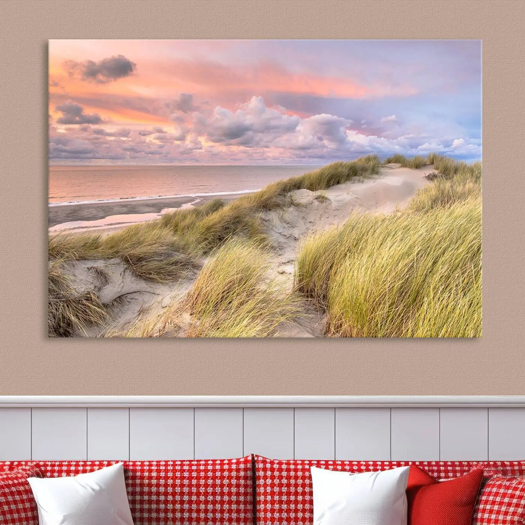 The Ocean Beach Wall Art Canvas Print Sunset Artwork captures a stunning sunset over sand dunes and grass, adding a touch of coastal charm to the room. This piece of wall art infuses any space with warmth and serenity.