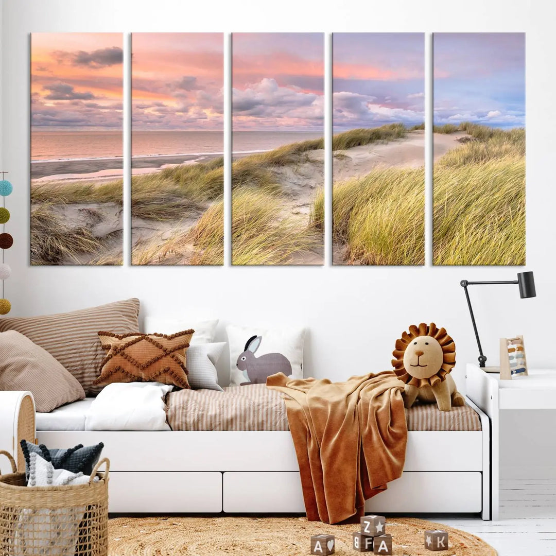 The Ocean Beach Wall Art Canvas Print Sunset Artwork captures a stunning sunset over sand dunes and grass, adding a touch of coastal charm to the room. This piece of wall art infuses any space with warmth and serenity.