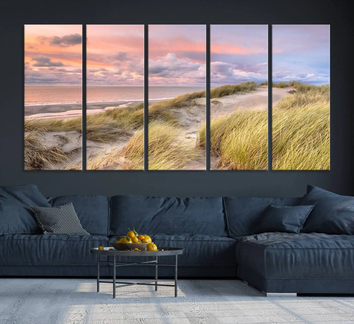 The Ocean Beach Wall Art Canvas Print Sunset Artwork captures a stunning sunset over sand dunes and grass, adding a touch of coastal charm to the room. This piece of wall art infuses any space with warmth and serenity.