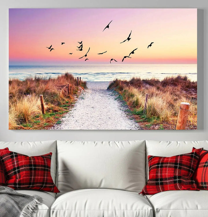 The "Ocean Pathway Sunset Canvas Art" beautifully depicts a tranquil coastal beach walk at sunset, featuring birds in flight across a vividly colorful sky. This piece is crafted using giclee print technology on canvas to ensure vibrant colors and exquisite detail for a relaxing wall art experience.