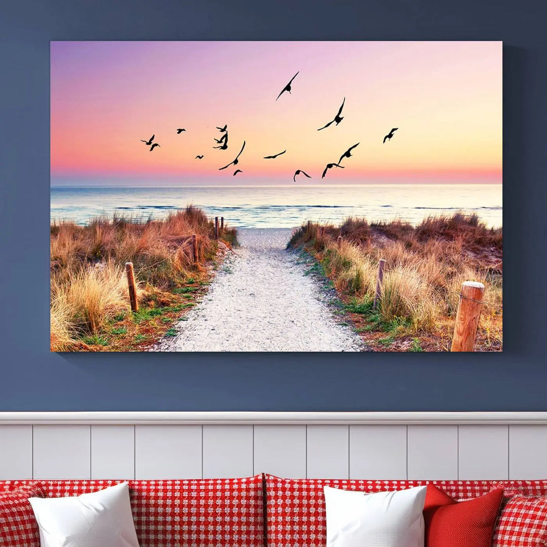 The "Ocean Pathway Sunset Canvas Art" beautifully depicts a tranquil coastal beach walk at sunset, featuring birds in flight across a vividly colorful sky. This piece is crafted using giclee print technology on canvas to ensure vibrant colors and exquisite detail for a relaxing wall art experience.