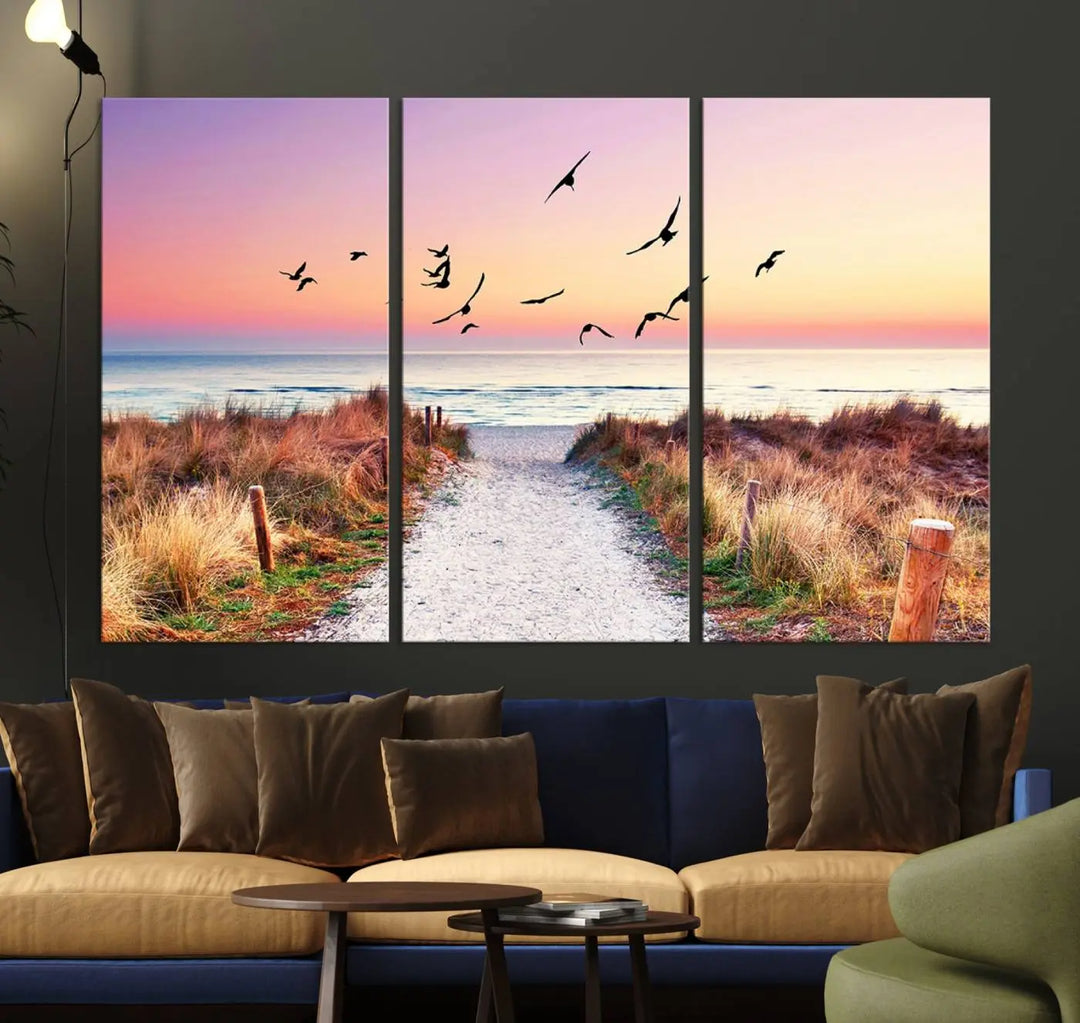 The "Ocean Pathway Sunset Canvas Art" beautifully depicts a tranquil coastal beach walk at sunset, featuring birds in flight across a vividly colorful sky. This piece is crafted using giclee print technology on canvas to ensure vibrant colors and exquisite detail for a relaxing wall art experience.