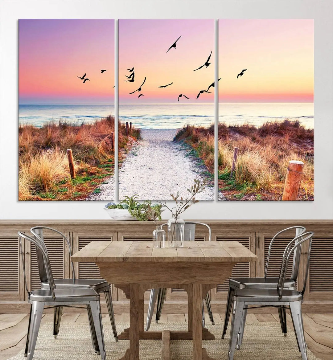 The "Ocean Pathway Sunset Canvas Art" beautifully depicts a tranquil coastal beach walk at sunset, featuring birds in flight across a vividly colorful sky. This piece is crafted using giclee print technology on canvas to ensure vibrant colors and exquisite detail for a relaxing wall art experience.