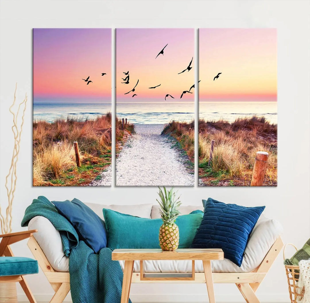 The "Ocean Pathway Sunset Canvas Art" beautifully depicts a tranquil coastal beach walk at sunset, featuring birds in flight across a vividly colorful sky. This piece is crafted using giclee print technology on canvas to ensure vibrant colors and exquisite detail for a relaxing wall art experience.