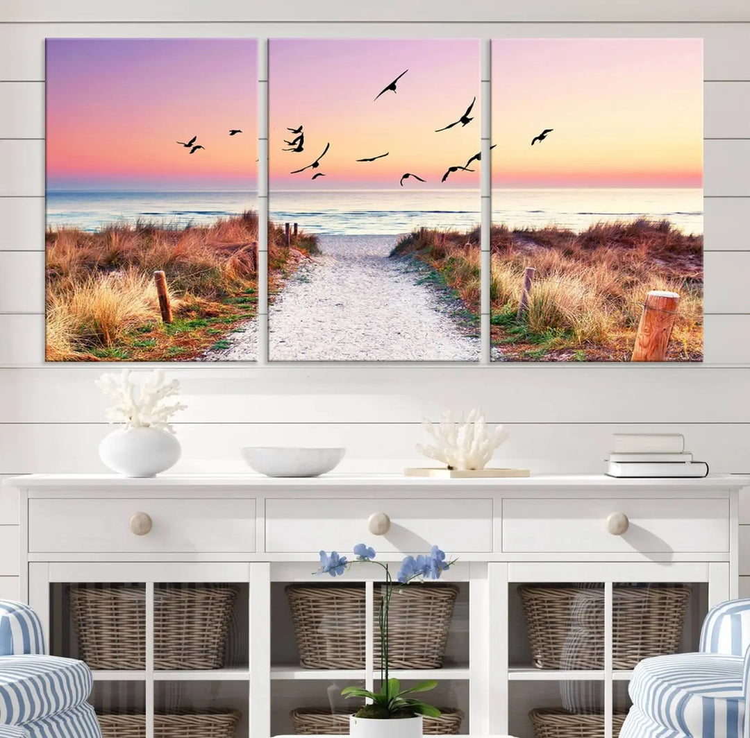 The "Ocean Pathway Sunset Canvas Art" beautifully depicts a tranquil coastal beach walk at sunset, featuring birds in flight across a vividly colorful sky. This piece is crafted using giclee print technology on canvas to ensure vibrant colors and exquisite detail for a relaxing wall art experience.