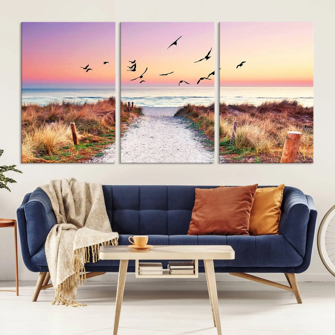 The "Ocean Pathway Sunset Canvas Art" beautifully depicts a tranquil coastal beach walk at sunset, featuring birds in flight across a vividly colorful sky. This piece is crafted using giclee print technology on canvas to ensure vibrant colors and exquisite detail for a relaxing wall art experience.