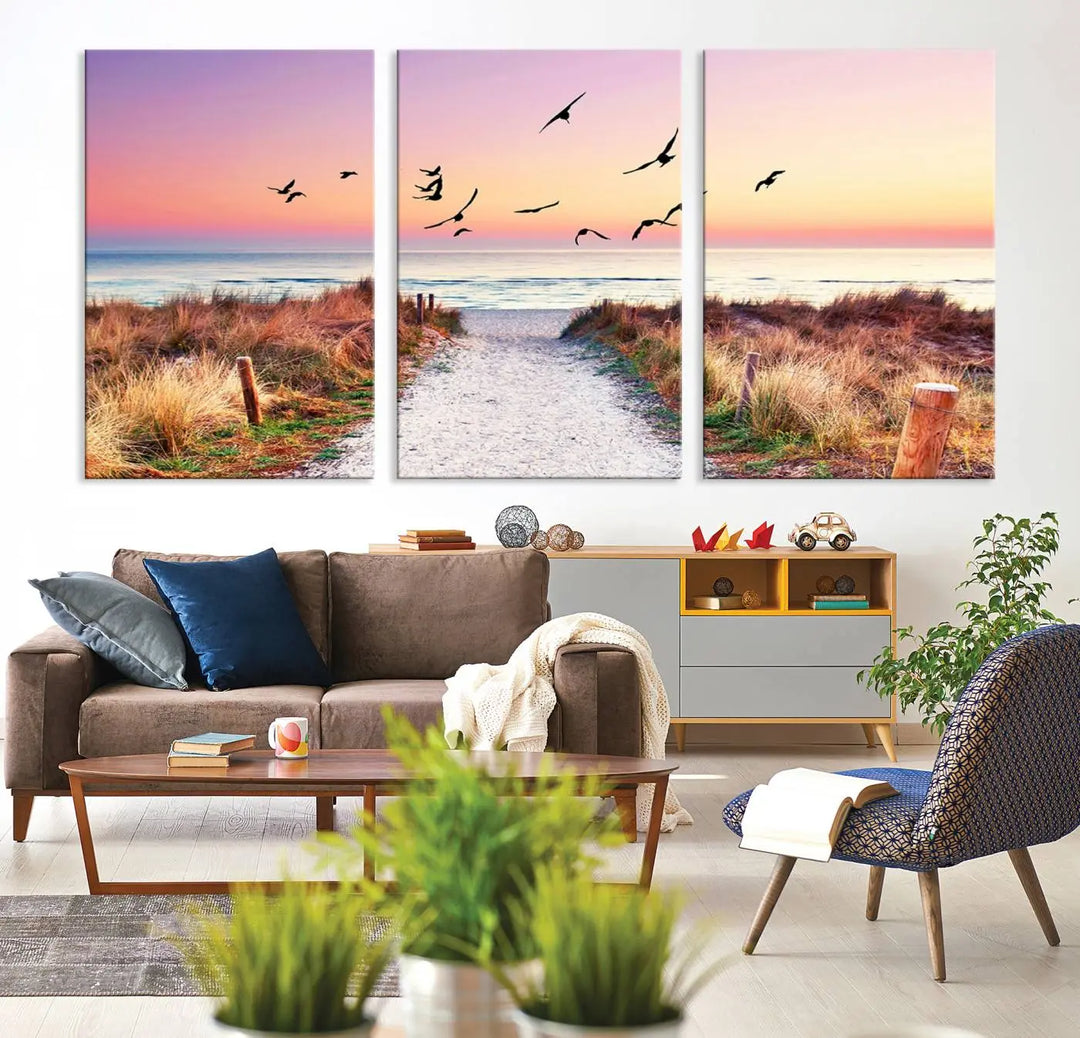 The "Ocean Pathway Sunset Canvas Art" beautifully depicts a tranquil coastal beach walk at sunset, featuring birds in flight across a vividly colorful sky. This piece is crafted using giclee print technology on canvas to ensure vibrant colors and exquisite detail for a relaxing wall art experience.