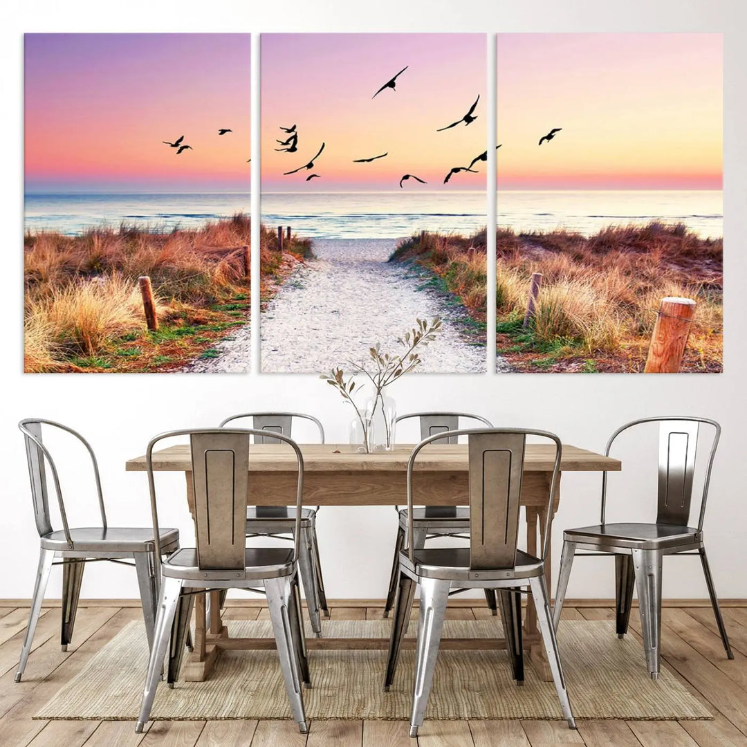 The "Ocean Pathway Sunset Canvas Art" beautifully depicts a tranquil coastal beach walk at sunset, featuring birds in flight across a vividly colorful sky. This piece is crafted using giclee print technology on canvas to ensure vibrant colors and exquisite detail for a relaxing wall art experience.