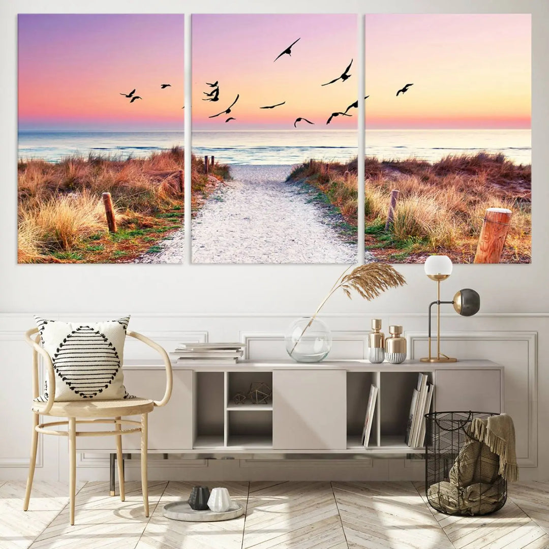 The "Ocean Pathway Sunset Canvas Art" beautifully depicts a tranquil coastal beach walk at sunset, featuring birds in flight across a vividly colorful sky. This piece is crafted using giclee print technology on canvas to ensure vibrant colors and exquisite detail for a relaxing wall art experience.