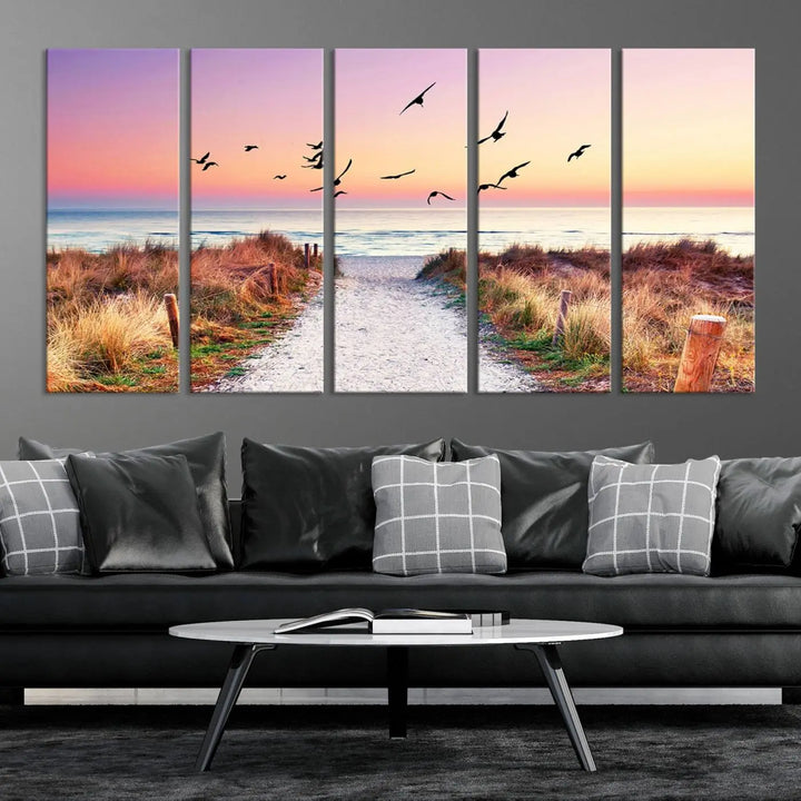 The "Ocean Pathway Sunset Canvas Art" beautifully depicts a tranquil coastal beach walk at sunset, featuring birds in flight across a vividly colorful sky. This piece is crafted using giclee print technology on canvas to ensure vibrant colors and exquisite detail for a relaxing wall art experience.