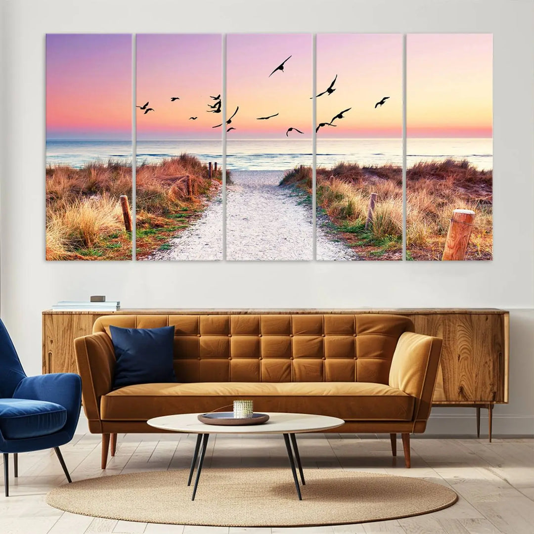 The "Ocean Pathway Sunset Canvas Art" beautifully depicts a tranquil coastal beach walk at sunset, featuring birds in flight across a vividly colorful sky. This piece is crafted using giclee print technology on canvas to ensure vibrant colors and exquisite detail for a relaxing wall art experience.