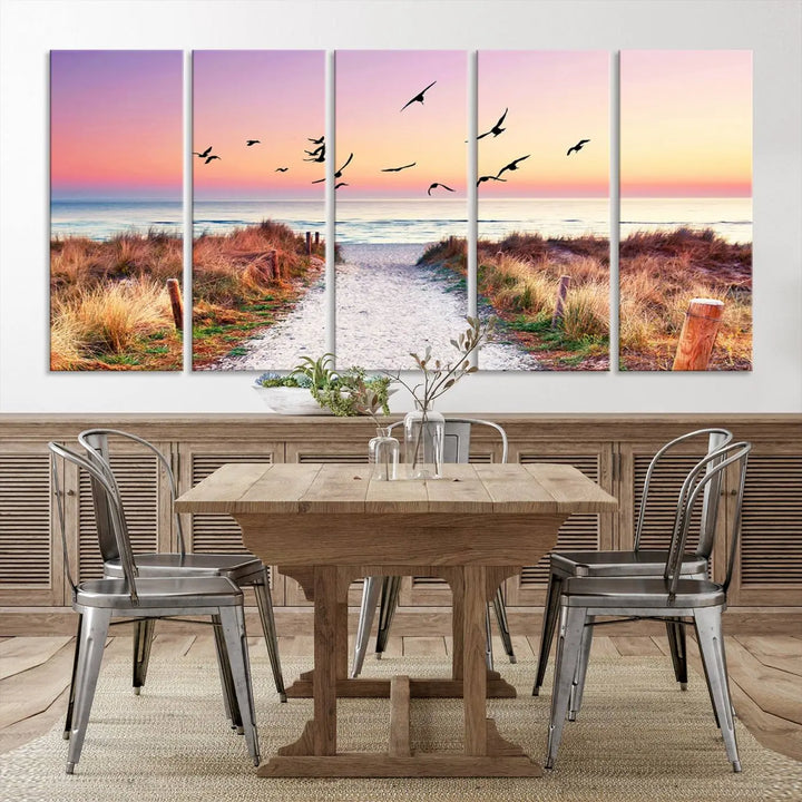 The "Ocean Pathway Sunset Canvas Art" beautifully depicts a tranquil coastal beach walk at sunset, featuring birds in flight across a vividly colorful sky. This piece is crafted using giclee print technology on canvas to ensure vibrant colors and exquisite detail for a relaxing wall art experience.